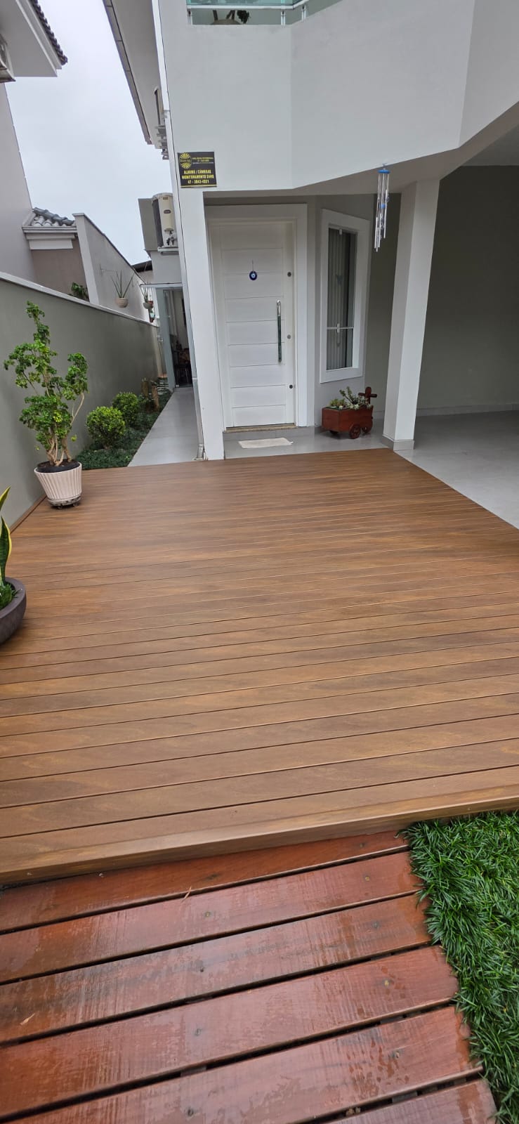 Deck em madeira plástica na entrada de residência com jardim lateral