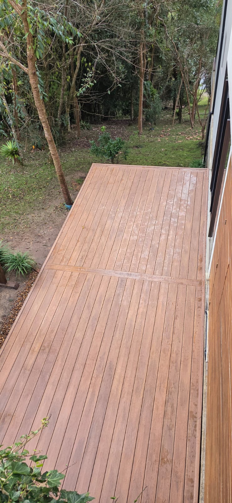 Deck em madeira plástica em corredor lateral com jardim e árvores