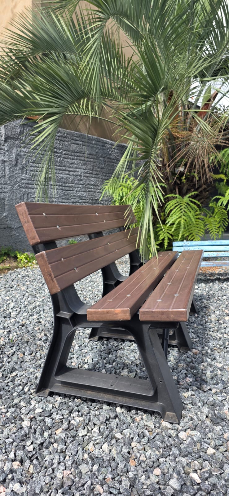 Banco em madeira plástica em jardim com palmeira